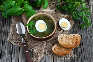 Fresh vegetable soup made of  potato and sorrel  in bow  lon old wooden table 