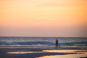silhouette d'un photographe devant un coucher de soleil au bord de l'océan