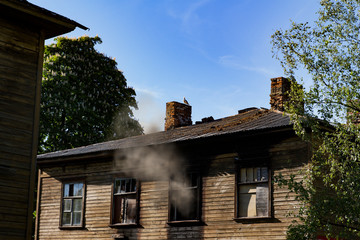 An old pre war wooden house after fire with smoke coming out of a window