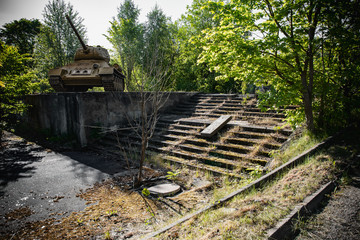 A tank standing and aiming by the damaged stairs of an abandoned and destroyed building ruins