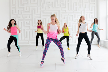 Group of happy young women in sportswear at dance fitness class in white fitness studio