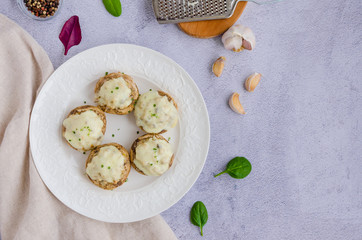Baked Stuffed mushrooms with onion, cream, garlic, thyme and cheese on a white plate. Horizontal orientation. Top view. Copy space.