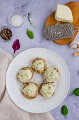 Baked Stuffed mushrooms with onion, cream, garlic, thyme and cheese on a white plate. Vertical orientation. Top view.
