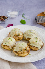 Baked Stuffed mushrooms with onion, cream, garlic, thyme and cheese on a white plate. Vertical orientation.