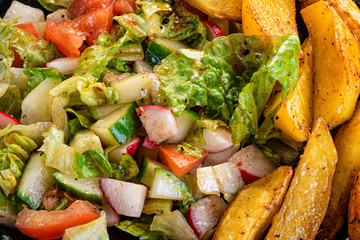 fresh vegetable salad and perfectly fireproof potato on a black plate
