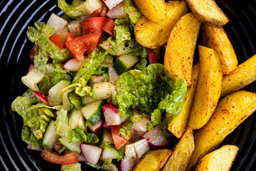 fresh vegetable salad and perfectly fireproof potato on a black plate