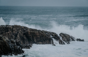 The waves of the ocean hit the rocks with small splashes