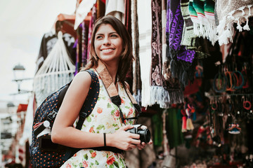 hispanic woman backpacker holding a camera in a traditional mexican Market in Mexico, Vacations