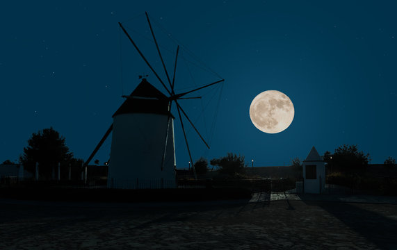 It is night and the full moon is shining. A beautiful old windmill near the town of Torre-Pacheco near Murcia on the Mediterranean. The lanterns on the sidewalk glow.