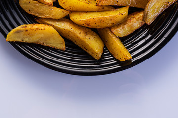 golden fried potatoes on a black plate, white background