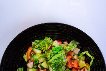 fresh salad from the vegetables of a black plate, white background