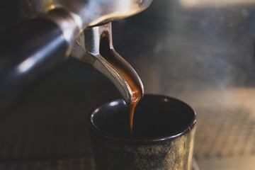 Nahaufnahme eines leckeren braunen Espressos, der frisch durch eine Siebträger Kaffeemaschine in eine Espressotasse läuft