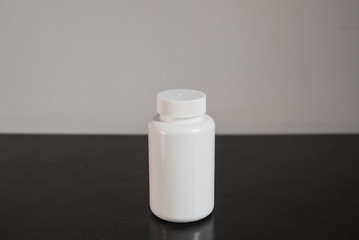 white plastic pills bottle on blacktable