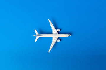 Naklejka premium The passenger plane on blue background with empty space for text. Top view, copy space