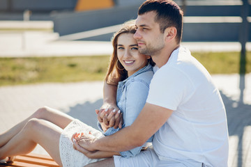 Couple in a park. Blonde in a blue shirt. Man in a white t- shirt