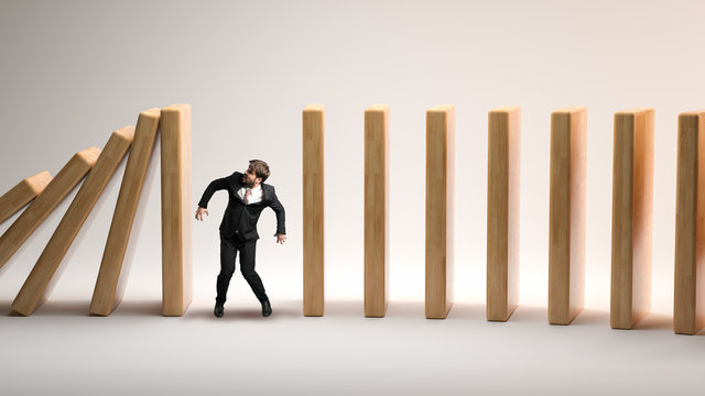 businessman as a stopper between falling domino-blocks on white background