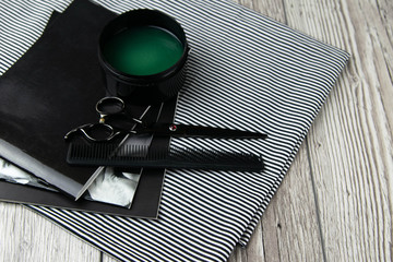 Scissors, dew and hair gel on a beautiful striped towel that stands on a wooden background