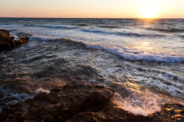 Beautiful sunset over wavy stormy Black sea rocky coastline in Crimea on summer day. Natural landscape background and wallpaper
