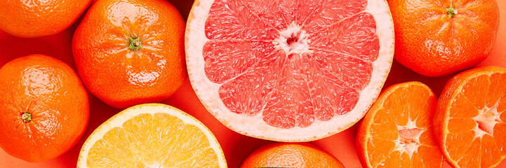 Banner with fresh ripe mandarins, grapefruit and oranges with green leaves on orange background.