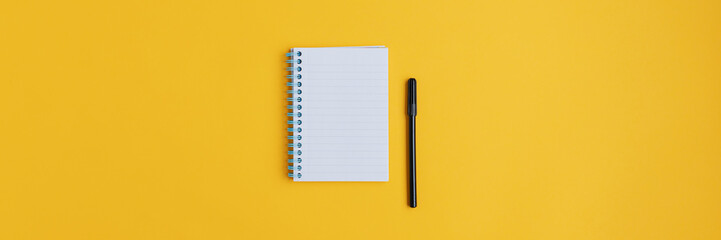 Wide view image of blank spiral note pad and black marker - obrazy, fototapety, plakaty