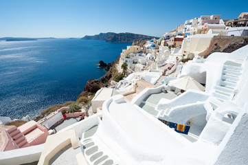 Fototapeta premium Classic Santorini staircases wind their way along bright morning hillside view of Oia village