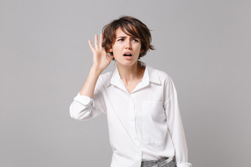 Bewildered young business woman in white shirt posing isolated on grey background studio portrait....