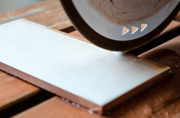 Ceramic tile cutting machine. Rotary cutting disc. Tile on the bed. Water supply.