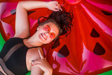 Happy teenage girl wearing red sunglasses floating with watermelon lilos, sea - having fun swimming...