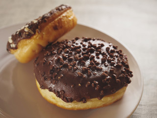 Two taste chocolate round doughnut on a white plate. Bakery product. Selective focus.