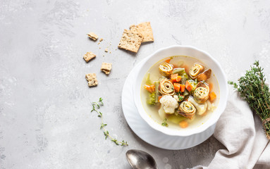 Vegetable soup with egg pancakes on light grey background. Traditional German Flaedlesuppe and Austrian Frittatensuppe. 