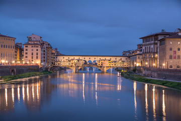 Fototapeta na wymiar Ponte Vecchio in historical center downtown in Florence during sunrise with water reflections in Arno river