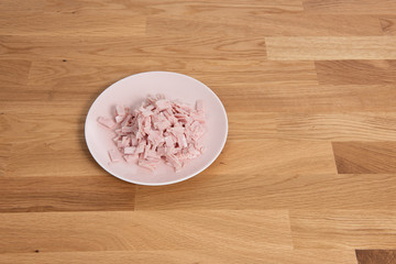 Plate of finely cut ham on a wooden table