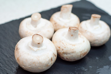 Porcini mushrooms lying washed on a dark stone surface, whole legs up.