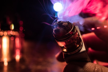 Vape concept. Electronic Cigarette vape explosion. Smoke clouds and vape liquid bottles on dark...