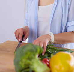 Young woman cutting vegetables in kitchen at home.