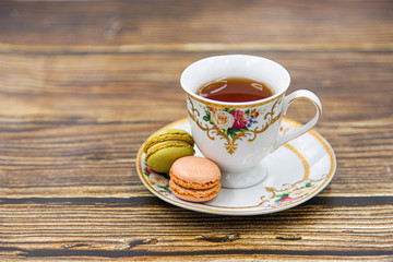 Cup of tea with macaroons on wooden background