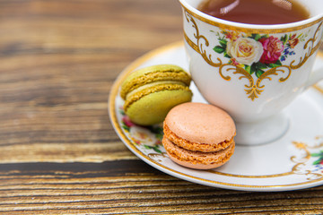 Cup of tea with macaroons on wooden background
