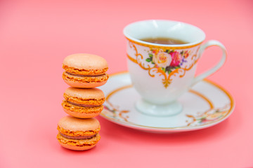 Cup of tea with Tasty Macaroon cookies  on pink background. closeup Assortment Almond Dessert macaroni.