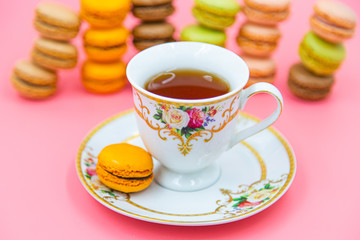 Cup of tea with Tasty Macaroon cookies  on pink background. closeup Assortment Almond Dessert macaroni.
