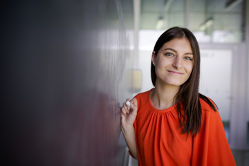 Pretty, young college student/young teacher writing on the chalkboard/blackboard during a math class