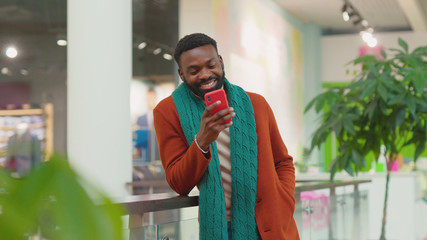 Portrait handsome african american young man use phone stand in mall Christmas time feel happy shopping internet face close up mobile technology close up slow motion