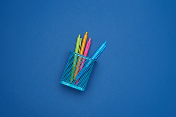 blue iron stand with multi-colored plastic ball pens on a blue background