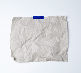 gray crumpled sheet of paper glued with blue adhesive tape