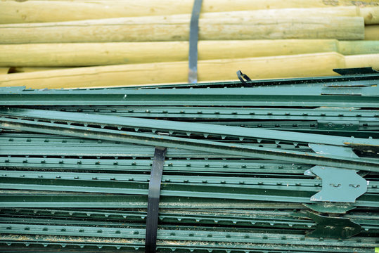 Closeup of wooden and metal fence posts horizontally stacked.