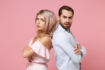 Perplexed young couple two guy girl in party outfit celebrating posing isolated on pastel pink background. People lifestyle Valentine's Day Women's Day birthday holiday concept. Holding hands crossed.