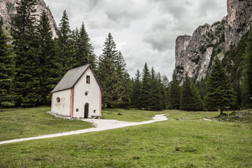 Fototapeta na wymiar An isolated little chapel (St. Silvester) among the woods in the Italian Dolomites