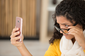 annoyed upset woman in glasses looking at smartphone with frustration