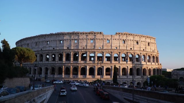4K: The Colosseum in Rome, Italy. Iconic Landmark - Blue Sky in the background. Tourists & traffic go by.
