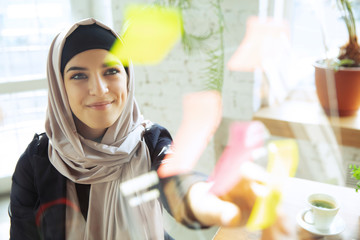 Organizing tasks. Portrait of a beautiful arabian businesswoman wearing hijab while working at openspace or office. Concept of occupation, freedom in business area, leadership, success, modern