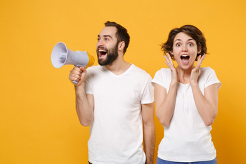 Excited young couple friends bearded guy girl in white blank empty t-shirts isolated on yellow...